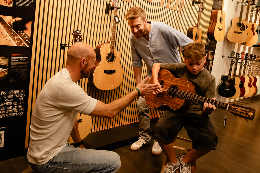 Specialisten helpen een jonge gitarist bij het kiezen van een gitaar