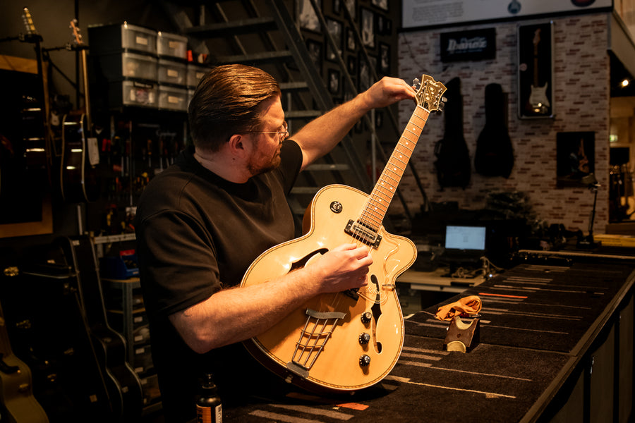 Gitaartechnicus controleert een hollowbody gitaar in de werkplaats